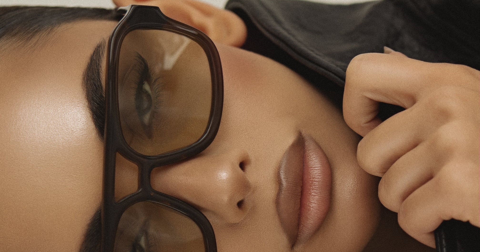 Person wearing large brown glasses with a neutral background